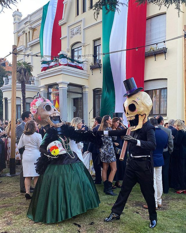 Calacas gigantes bailan en una fiesta con banderas de México